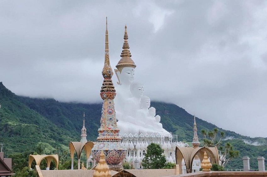 Une statue de Bouddha blanche, ornée de flèches dorées, se dressant sur un fond de montagnes. 3