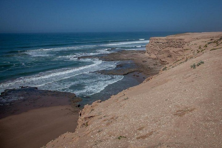 Un paisaje costero con acantilados rocosos y una playa de arena. 3