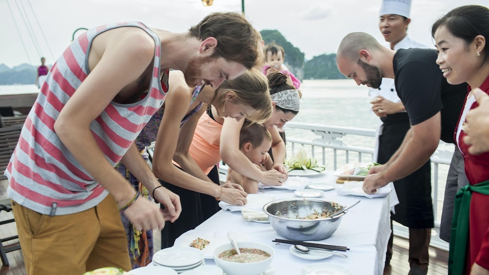 Een groep mensen dineert buiten aan een meer. 2
