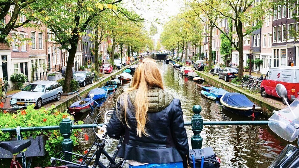 A canal with boats, a person on a bicycle, and buildings along the water. 2