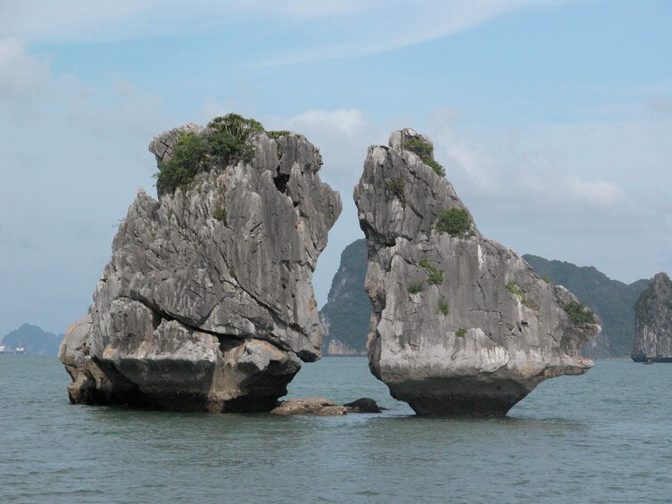 Due imponenti formazioni rocciose emergono da un corpo d'acqua, con montagne sullo sfondo. 2