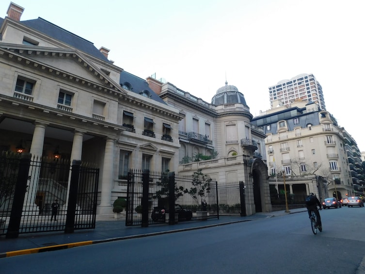 A historic building with classical architecture, a cyclist on the street, and modern high-rise buildings in the background. 5