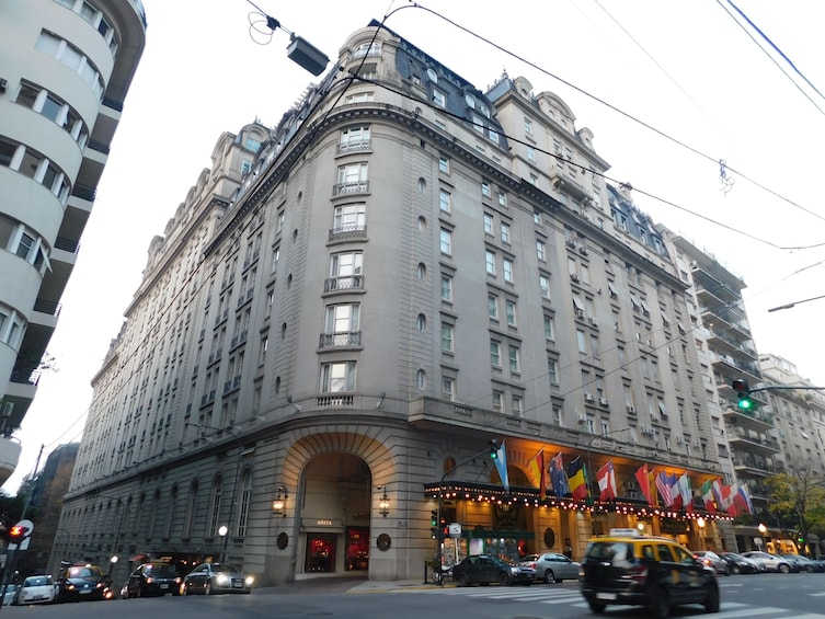 A large, historic building with multiple floors and balconies, featuring a grand entrance and a colorful marquee. 4