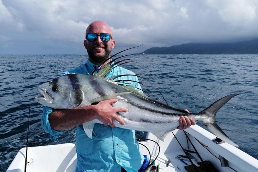 Eine Person hält einen großen Fisch auf einem Boot im Meer. 1