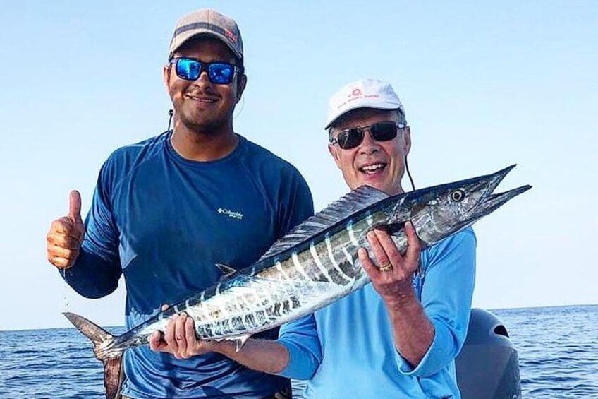 Two people holding a large fish on a boat in the ocean. 2