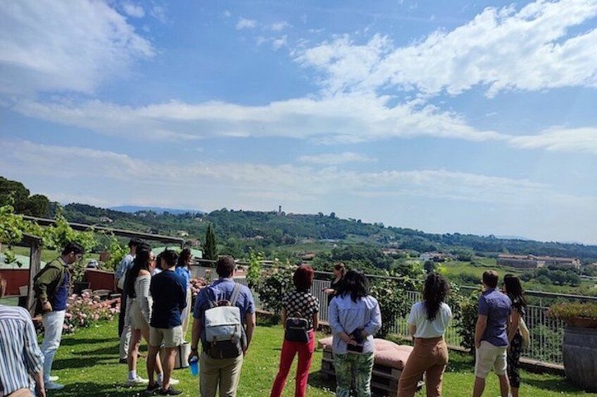 A group of people standing on a grassy area overlooking a scenic landscape with hills and a clear sky. 2