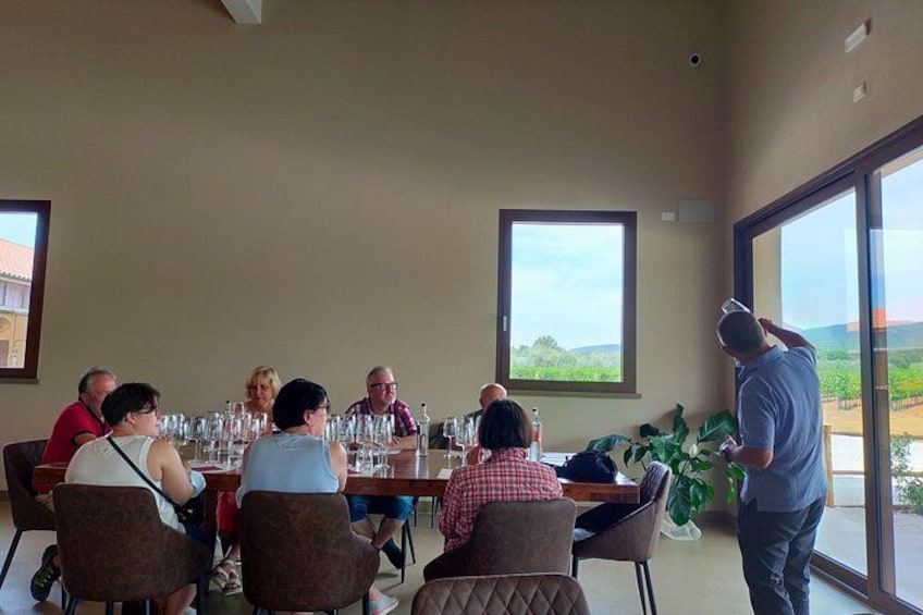 Un grupo de personas sentadas a una mesa dentro de un edificio con ventanas amplias. 4