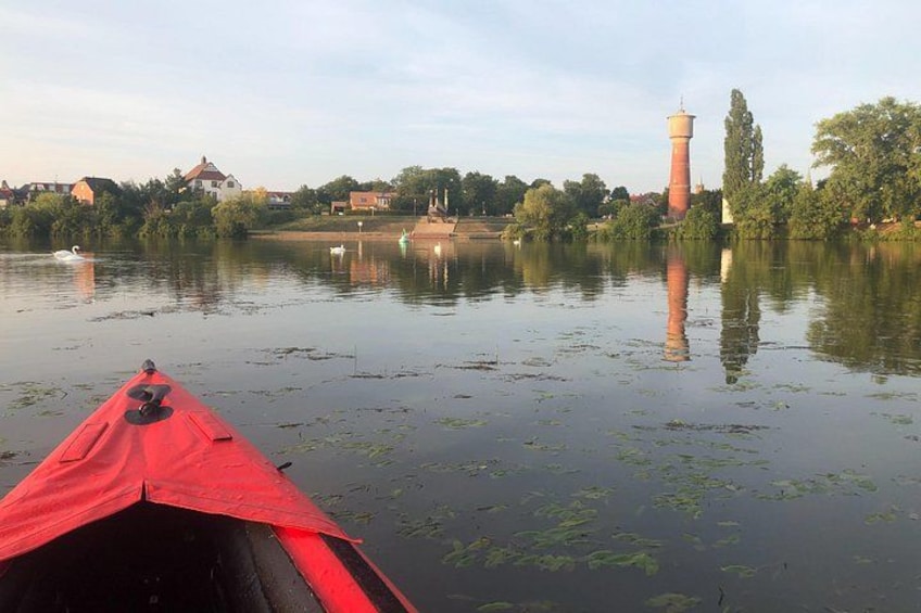 Un lago tranquilo con un kayak rojo, una torre y un cisne. 1