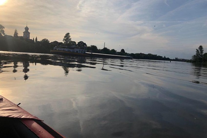 Un río tranquilo con un bote, una iglesia y árboles al fondo. 5