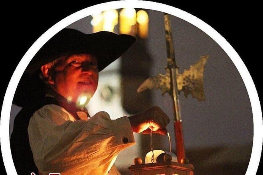 A person in a white shirt and black hat lighting a candle on a stand with a decorative item. 2