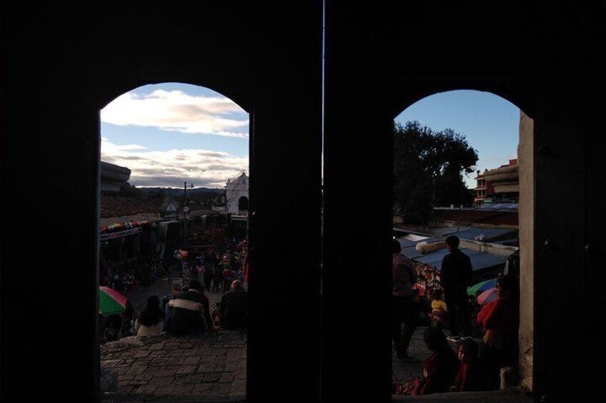 An archway leading to a bustling outdoor market with people and stalls. 1