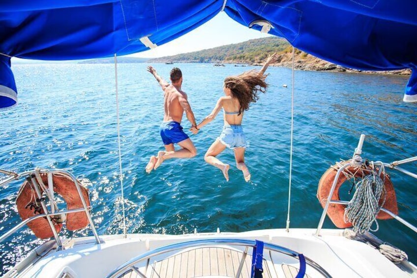 Twee personen springen vanaf een boot in het water. 1