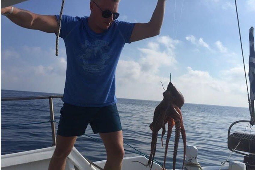 En person på en båt som håller i en stor bläckfisk. 3