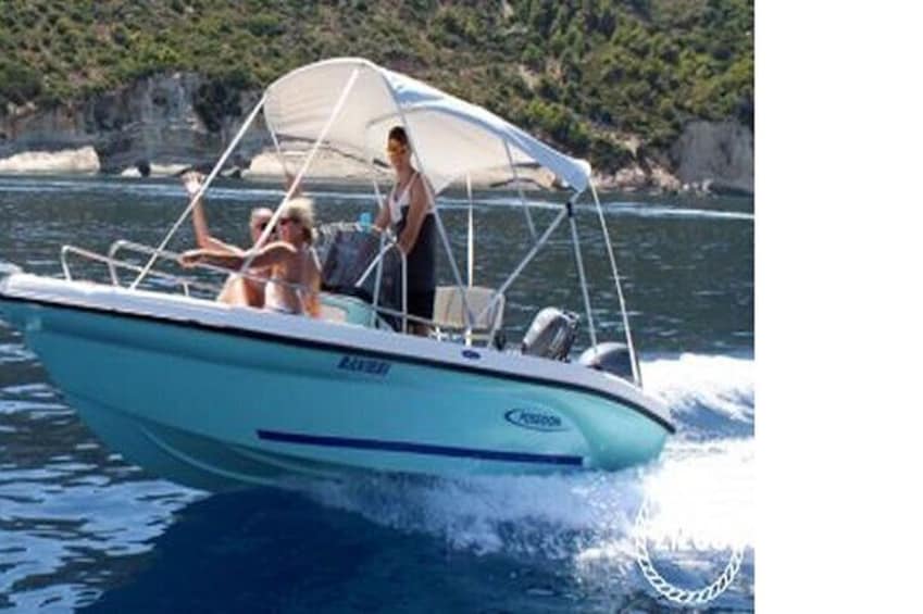 A boat with a canopy, two people, and a rocky coastline in the background. 5