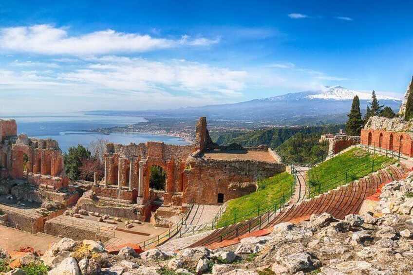 Ancient ruins with a theater, a mountain in the background, and a body of water. 1