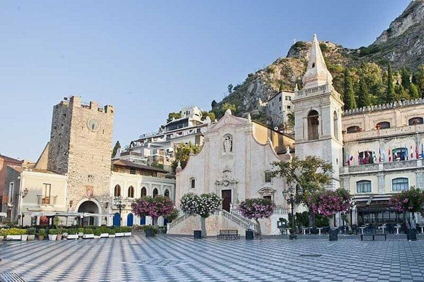 A historic town square with a prominent church, a castle tower, and a mountain backdrop. 5