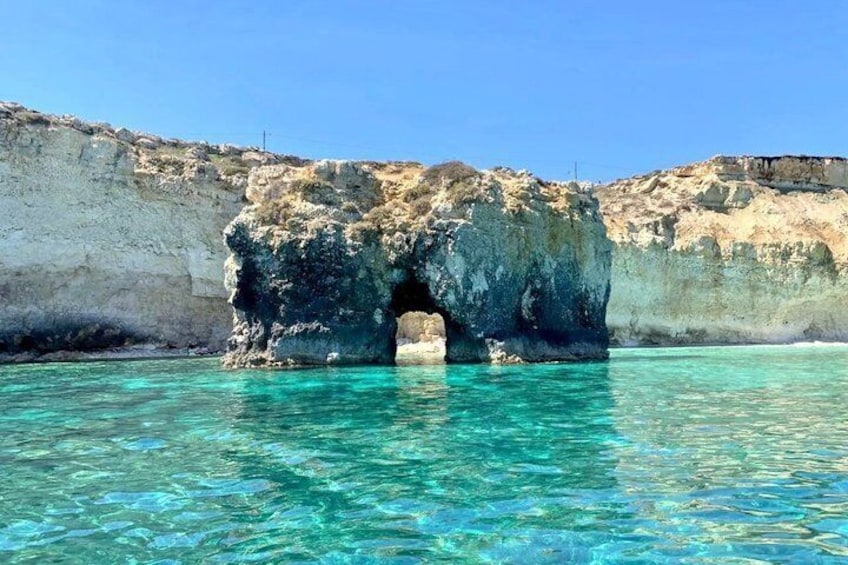 A clear blue sea with a rocky formation featuring a natural arch. 1