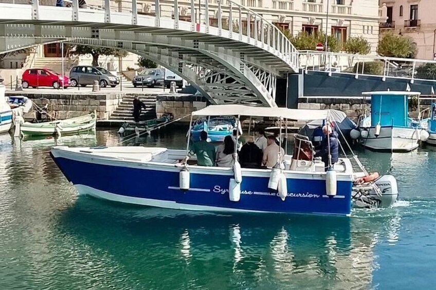 Ein blaues Boot namens 'Syracuse' auf einem Kanal, im Hintergrund eine Brücke. 4