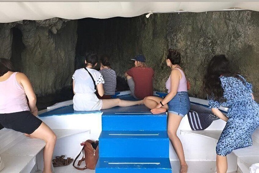 Menschen sitzen in einem Boot vor einer felsigen Kulisse. 2