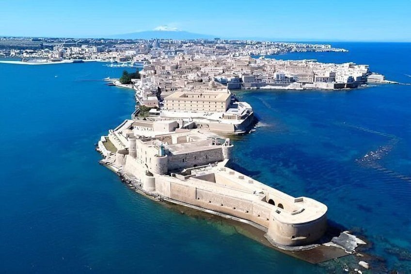 An aerial view of a fortified coastal city with a prominent sea wall and a large ship docked at the harbor. 4