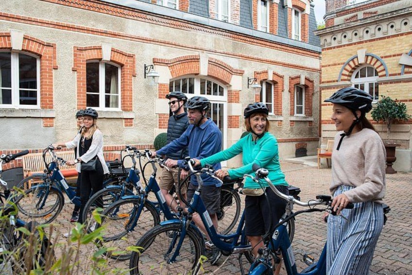 Un groupe de personnes à vélo se trouve devant un bâtiment à l’architecture en briques. 3