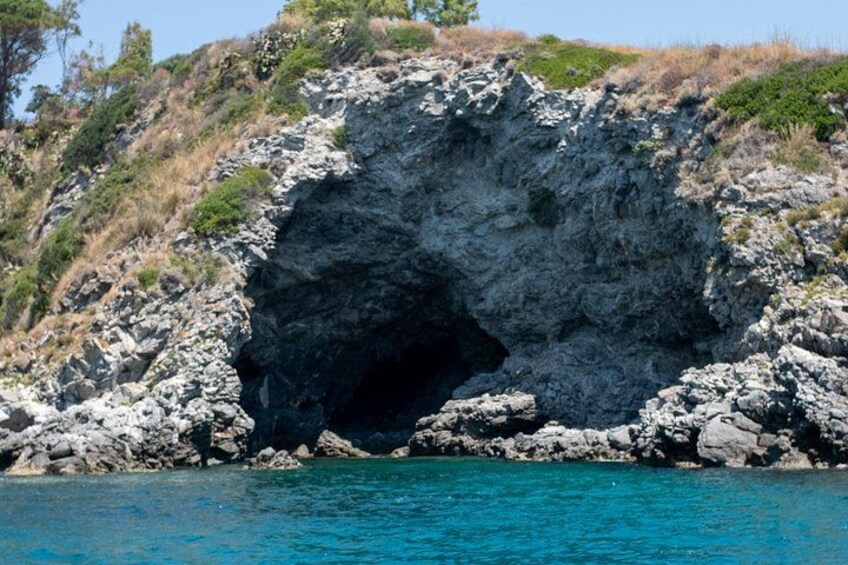 A rocky coastal landscape with a large cave opening. 5
