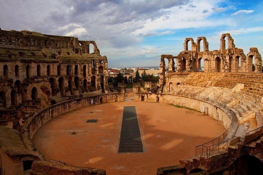 An ancient Roman amphitheater with a central stage and multiple tiers of seating. 4