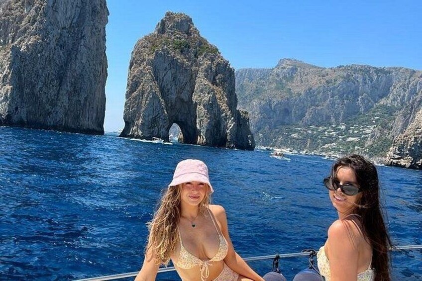 Dos personas en un bote con una costa rocosa y una formación parecida a una cueva al fondo. 1