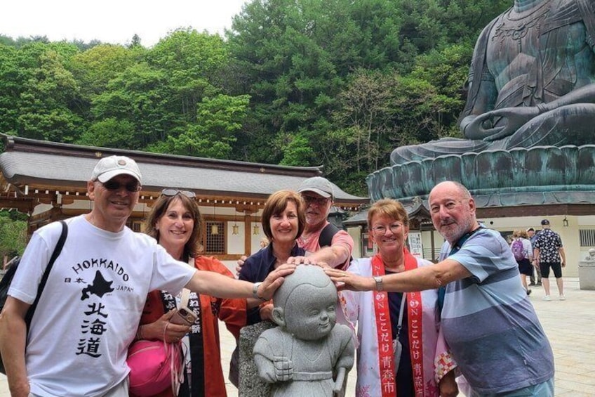 A group of people posing in front of a large Buddha statue and a traditional Japanese building. 1