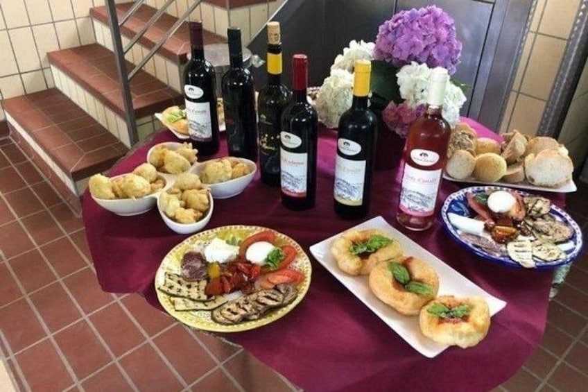 A table with food, wine bottles, and flowers. 5