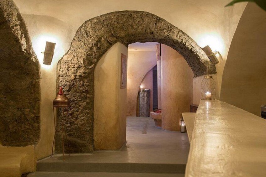 Un arco de piedra que da acceso a una habitación con una larga mesa y un banco. 3