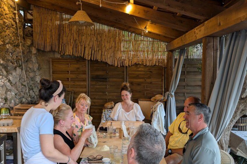 Un groupe de personnes est assis autour d’une table en bois, dans un cadre rustique caractérisé par un toit de chaume et des murs en pierre. 2