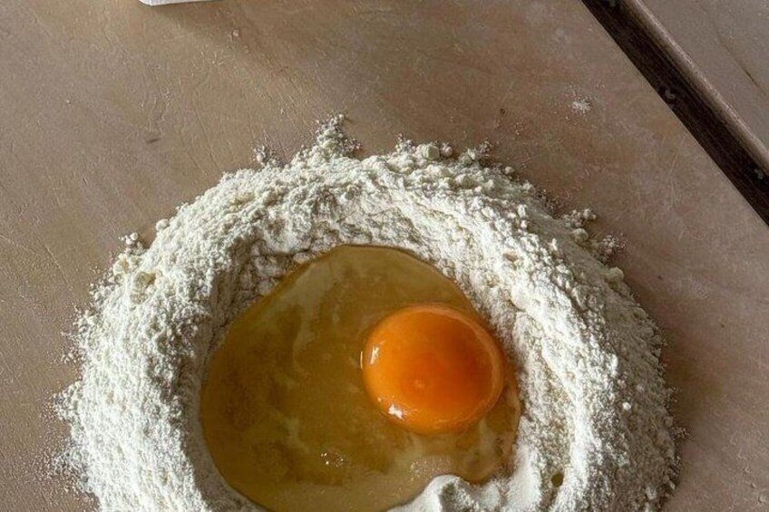 Un œuf cru posé sur un tas de farine, sur un plan de travail de cuisine. 2