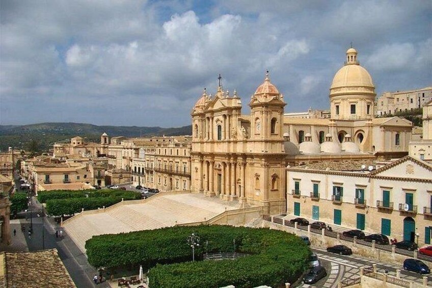 Una catedral histórica con una cúpula grande y torres de campanas, rodeada por un paisaje urbano con edificios y cielo despejado. 2
