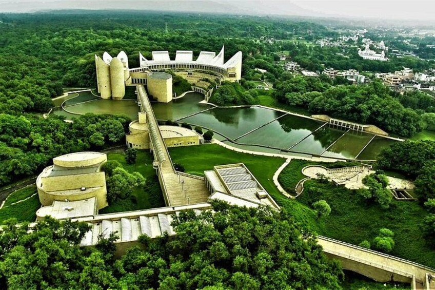 Ett stort, modernt arkitektoniskt komplex med flera byggnader, en flod och omgivande grönska. 2