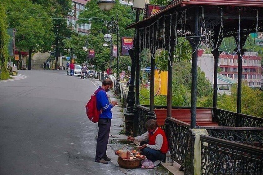 A street with a covered area where a person is sitting and another is standing. 4
