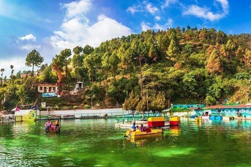 A calm lake with boats, surrounded by lush greenery and a clear sky. 2