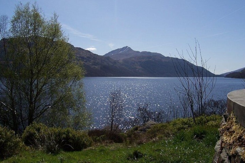 Un lago circondato da vegetazione, con montagne sullo sfondo e un cielo sereno. 1