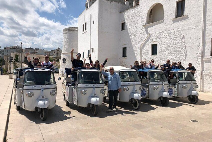 Un grupo de personas en autos antiguos frente a un edificio blanco con una torre. 2