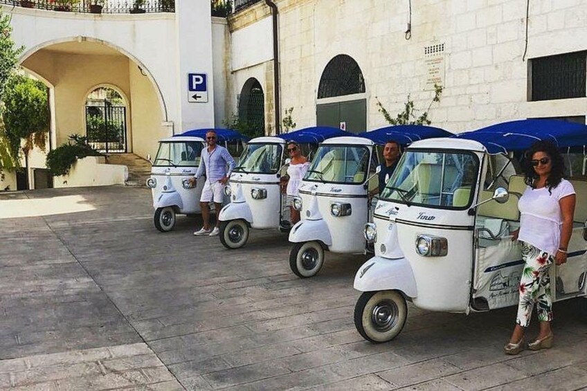Tres autos antiguos estacionados frente a un edificio con un letrero azul de estacionamiento. 4