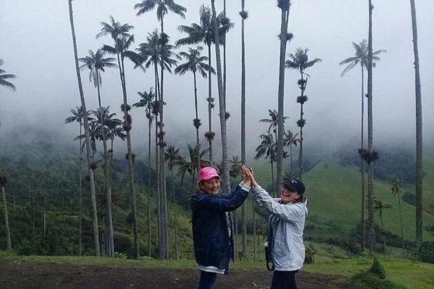 Two people taking a photo with palm trees in the background. 2