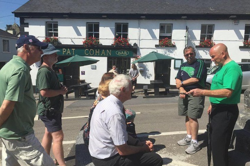 En gruppe mennesker står uden for en bygning, hvor der står 'PAT COHAN BAR' på et skilt. 4