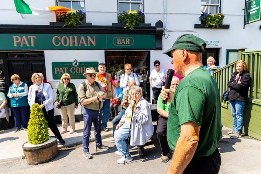 En man talar till en folkmassa framför en bar som heter ”Pat Cohan Bar”. 2