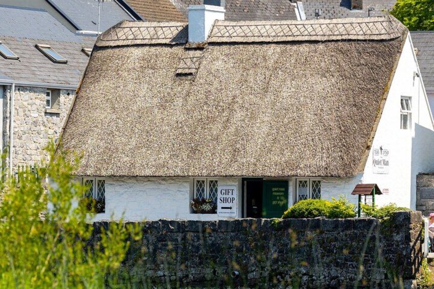 A white building with a thatched roof, a stone wall in front, and a sign that reads 'GIFT SHOP'. 3