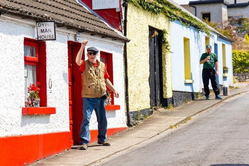 A person standing in front of a building with a sign that reads 'DYING MAN HOUSE.' 5