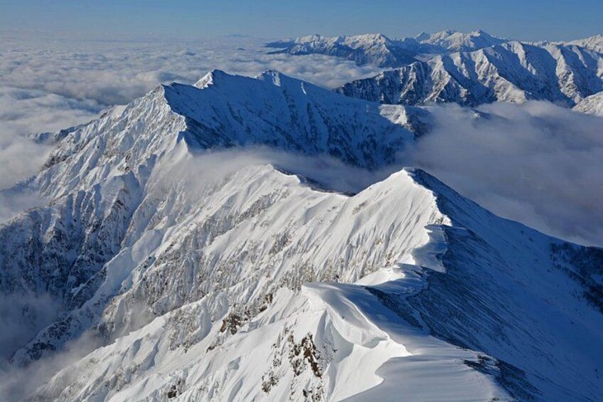 A snow-covered mountain peak with sharp ridges and a clear sky. 5