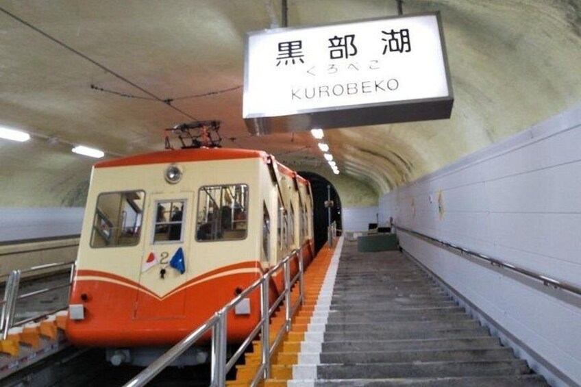 A train at a station with a sign reading 'KUROBEKO'. 3
