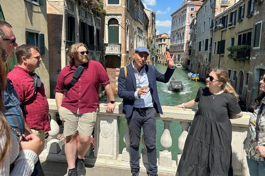 A group of people standing on a bridge in a canal with buildings on either side. 4