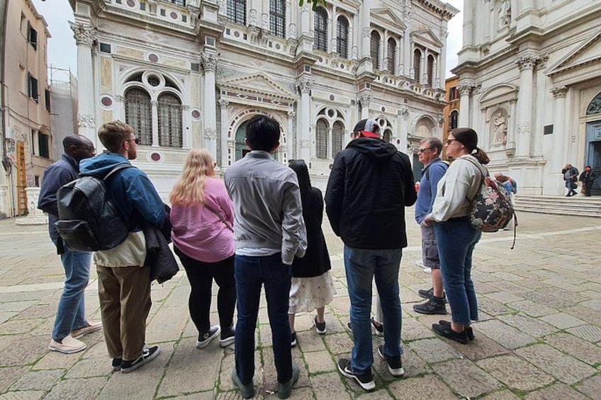 A group of people standing in a square with a historic building in the background. 2