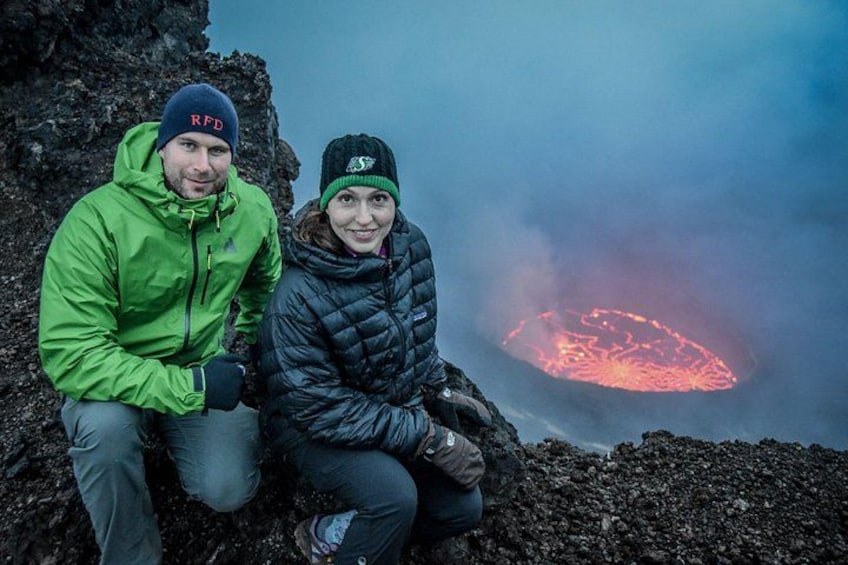 To personer sidder på en klippe med et glødende lava bassin i baggrunden. 1